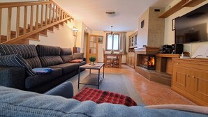 A cozy living room with a sofa, a coffee table, and a fireplace. - This is a peaceful place to stay: relax with the whole family! (Urroz-Villa)