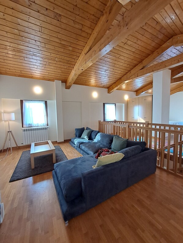 A modern living room with a wooden ceiling, a dark blue sofa, a small coffee table, and a view of the outdoors through a window.