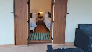 A hotel room with two beds, a nightstand with a lamp, and a small seating area with a bench. - This is a peaceful place to stay: relax with the whole family! (Urroz-Villa)