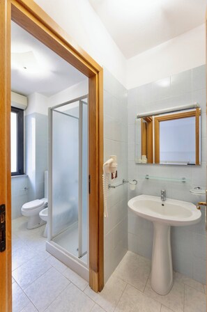 A modern bathroom with a glass shower enclosure, a pedestal sink, and a mirror above it. -  Apartments in Alghero just 150 mt from the sea (Alghero)
