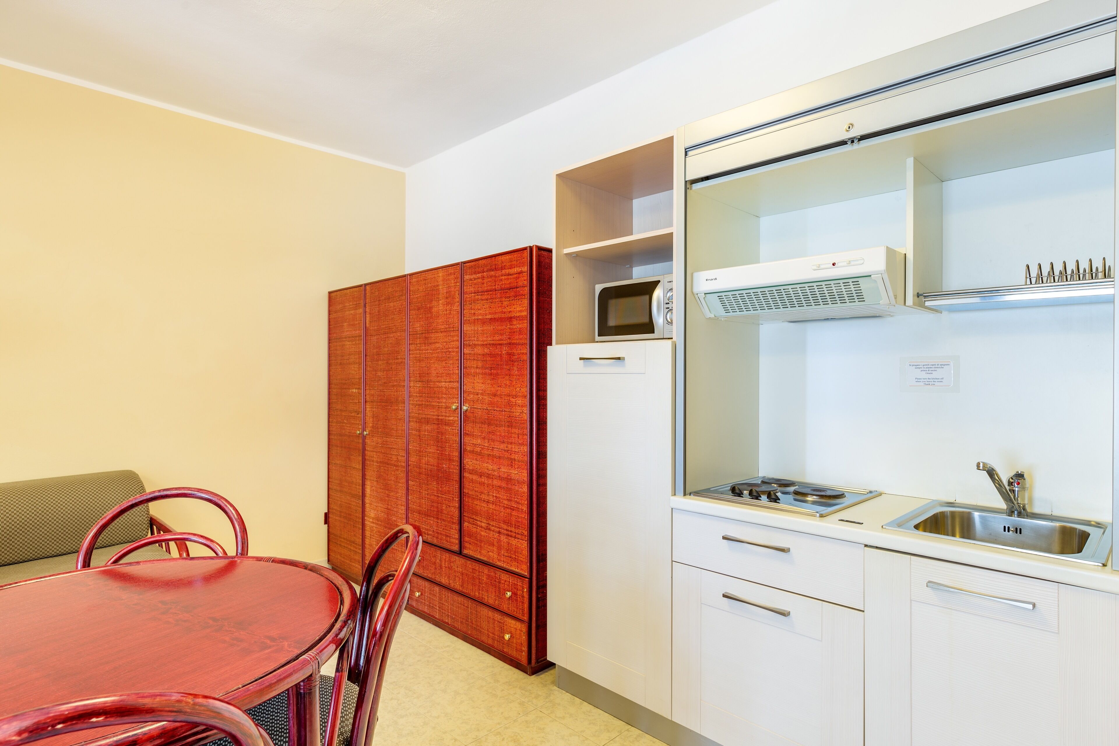 Cuina compacta amb taula de dinar, cadires, microones, nevera i un rentaplat.