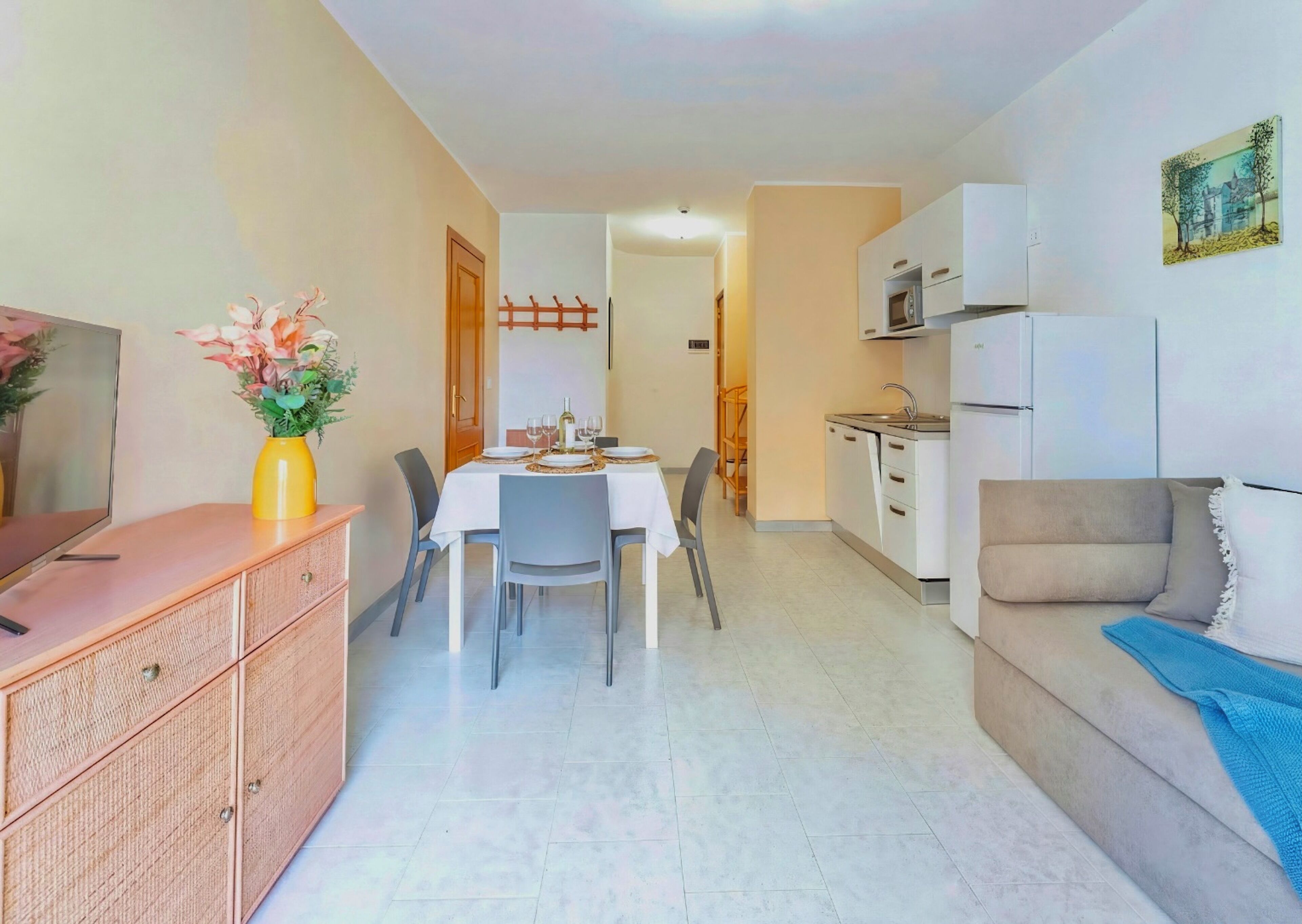 A compact living space with a dining area, kitchenette, and a sofa.