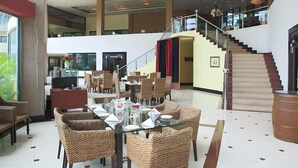 A spacious lobby with high ceilings, a staircase, and wicker furniture. - Swiss Traffalgaar Luxury Hotels (Nashik)