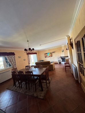 A dining area with a table and chairs, a sofa, and a fireplace. - QUINTA DO RIBEIRINHO (Gaviao)