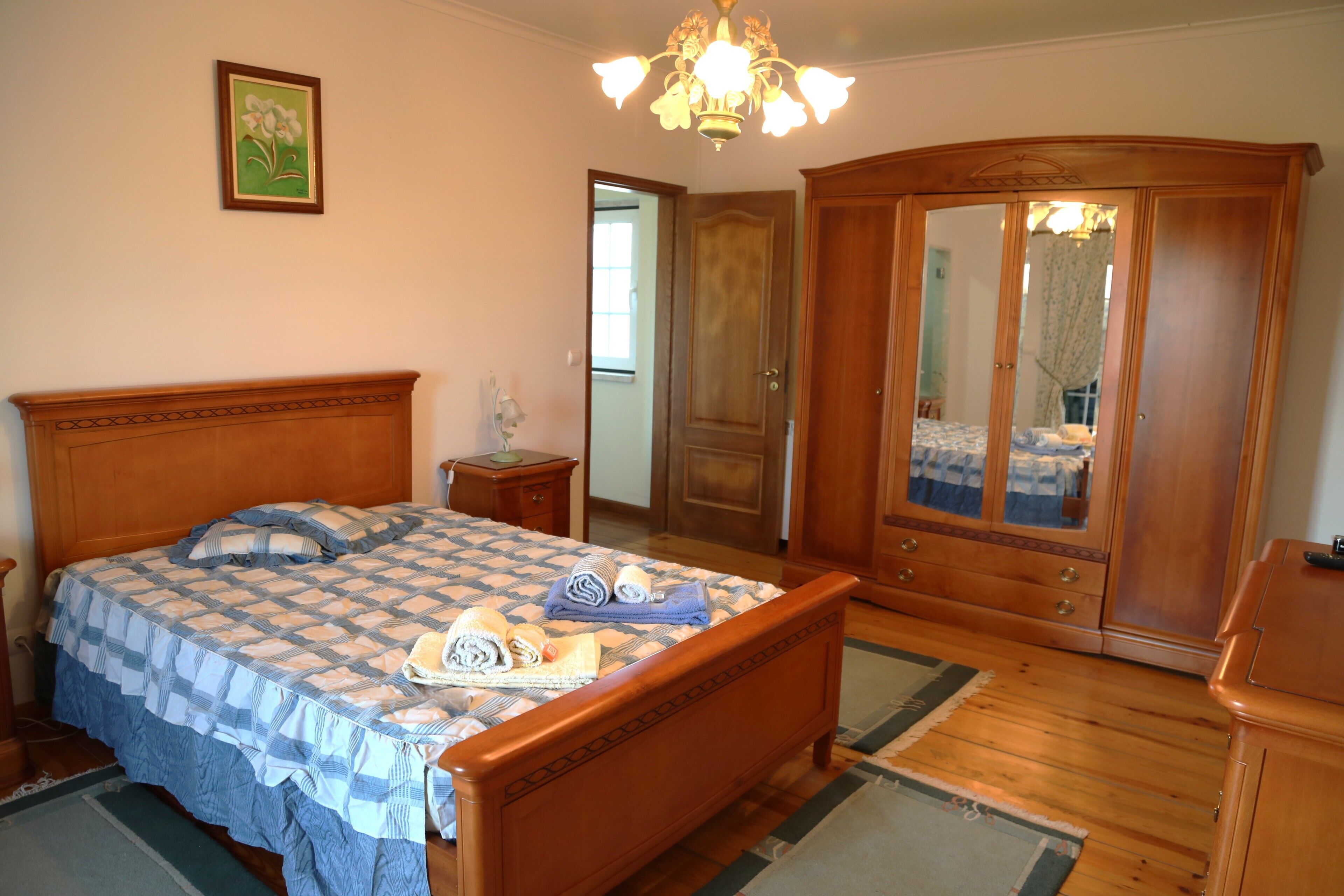 Ein Schlafzimmer mit einem hölzernen Bett, einem Schrank aus Holz, einem Spiegel und einer Chandelüster.