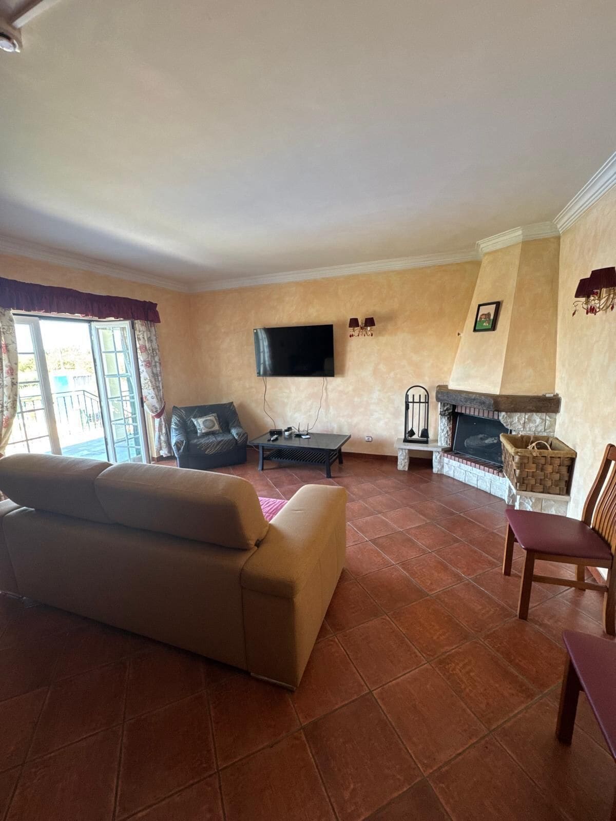 A living room with a sofa, a television, a fireplace, and a window with curtains.
