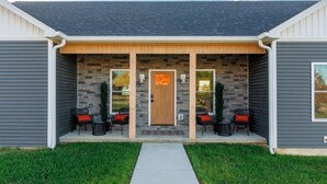 A house with a stone facade, a front porch with chairs, and a door.