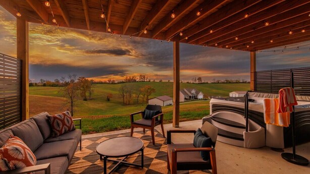 An outdoor patio with a checkered floor, a sofa, chairs, and a barbecue area.