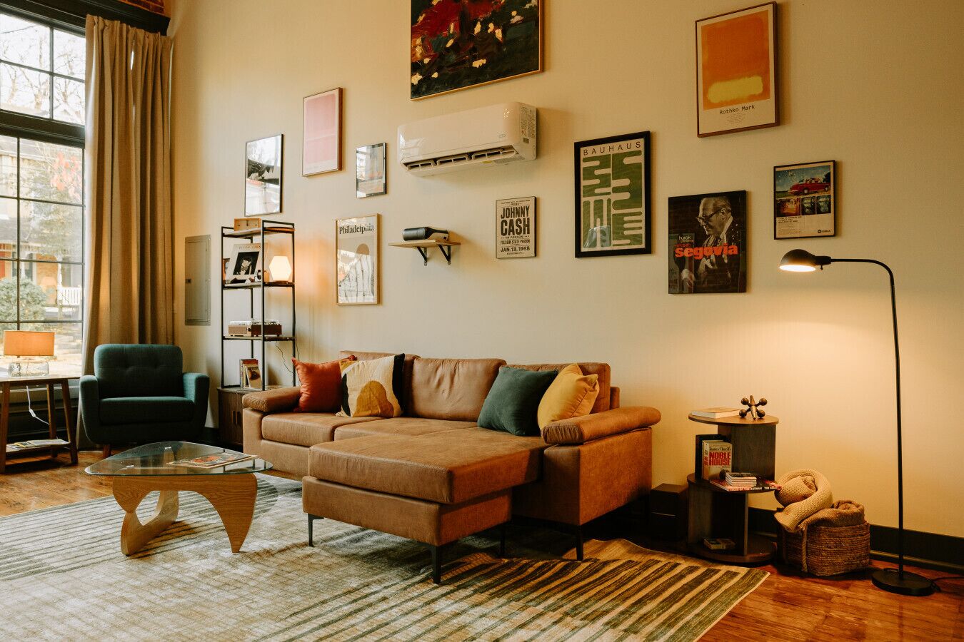 Een gezellige woonkamer met een bruine bank, een glazen salontafel en een boekenkast.