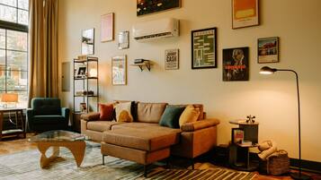Een gezellige woonkamer met een bruine bank, een glazen salontafel en een boekenkast.