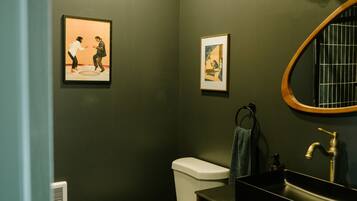 A bathroom with a toilet, sink, and framed artwork on the wall.