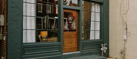 A building with a green facade, large windows, and a wooden door.