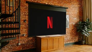 A brick wall with a large flat-screen TV displaying the Netflix logo.