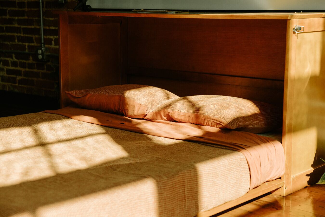 Een bed met een houten hoofdbord, een kussen en een dekbed.