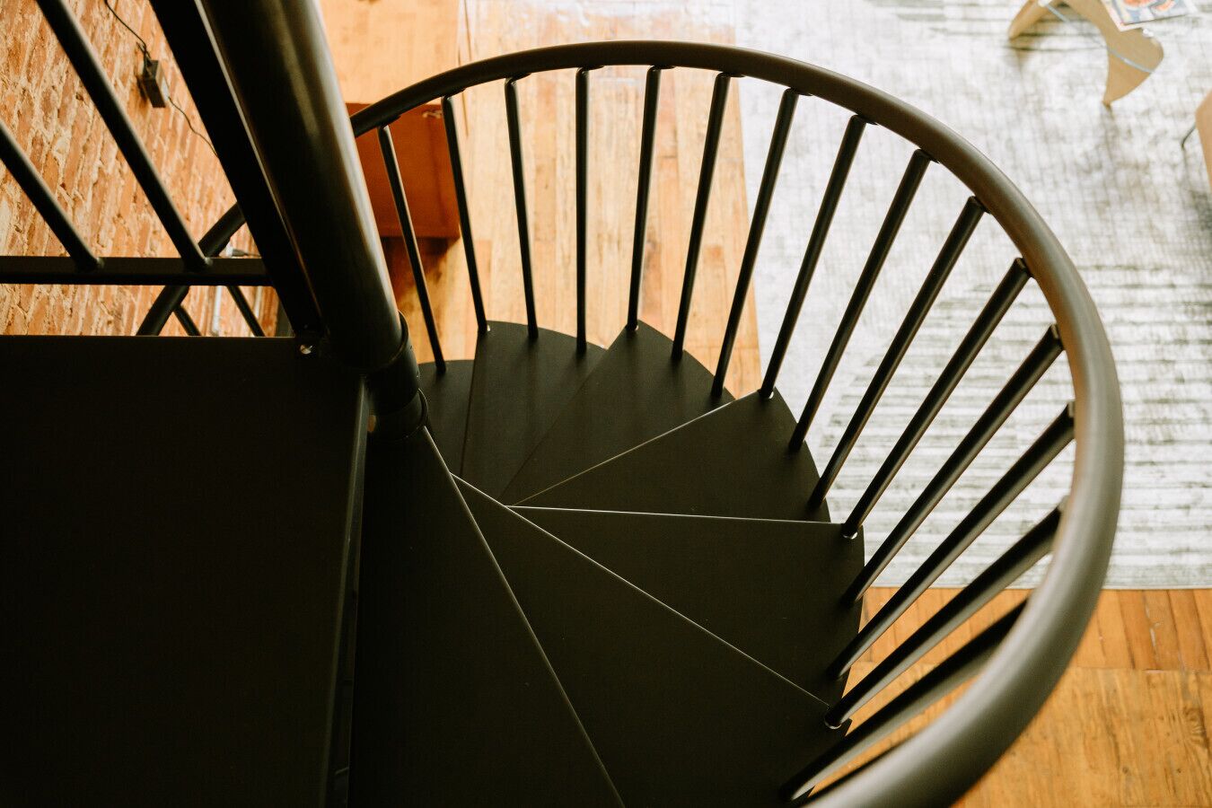 En spiralformet trappe med sort gelænder og trin, der fører nedad.