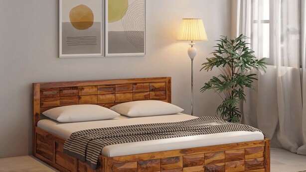Una camera da letto con una testiera in legno, un letto con biancheria bianca, una lampada da terra e una pianta in vaso.