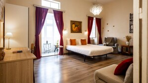 A hotel room with a bed, a desk, a chair, a sofa, a chandelier, and a painting on the wall. - Sliema 1BR Townhouse Escape (Sliema)