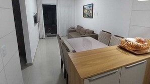 A modern kitchen with a wooden countertop and a dining table. There is a basket of bread on the table.