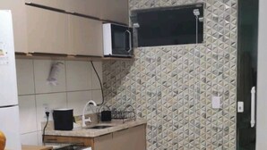 A compact kitchen with a microwave, stove, and sink.