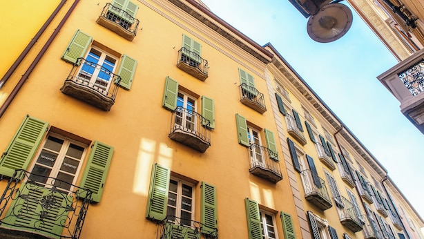 A building with multiple windows, some with green shutters, and balconies with metal railings. - Centro Storico (Como)
