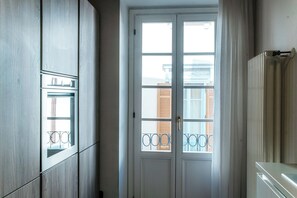 A room with a large window, a radiator, and a door with a metal gate. - Centro Storico (Como)