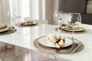 A dining table set with white plates, silverware, and wine glasses, with a woven placemat and a napkin ring. - Centro Storico (Como)