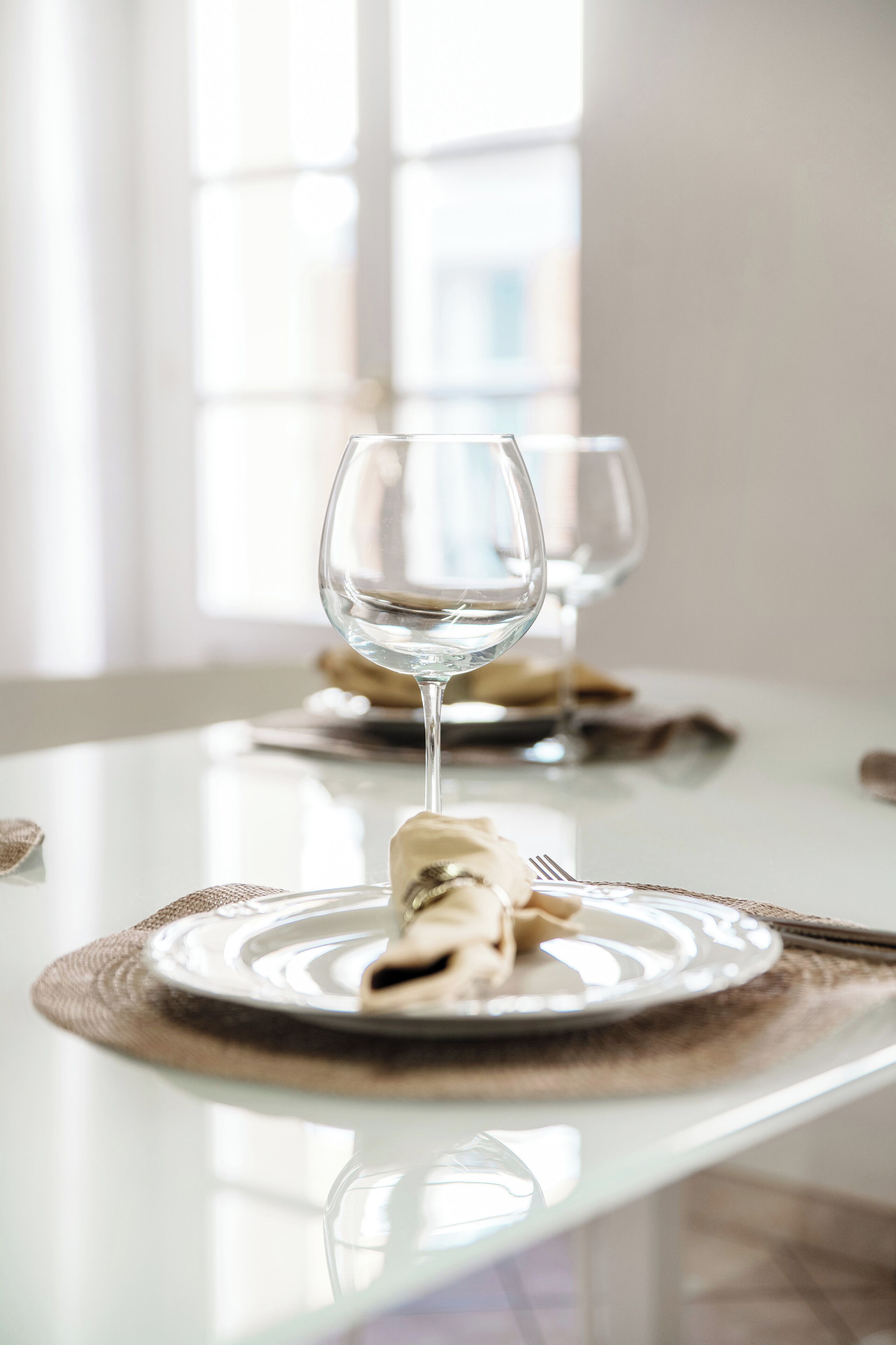 A dining table with a plate of food and a wine glass.