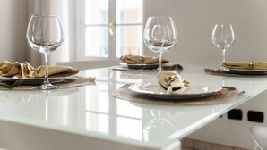 A dining table with three wine glasses, plates, and folded napkins. - Centro Storico (Como)