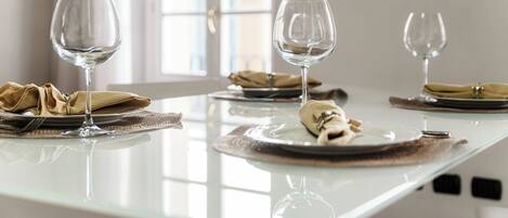 A dining table with three wine glasses, plates, and folded napkins.