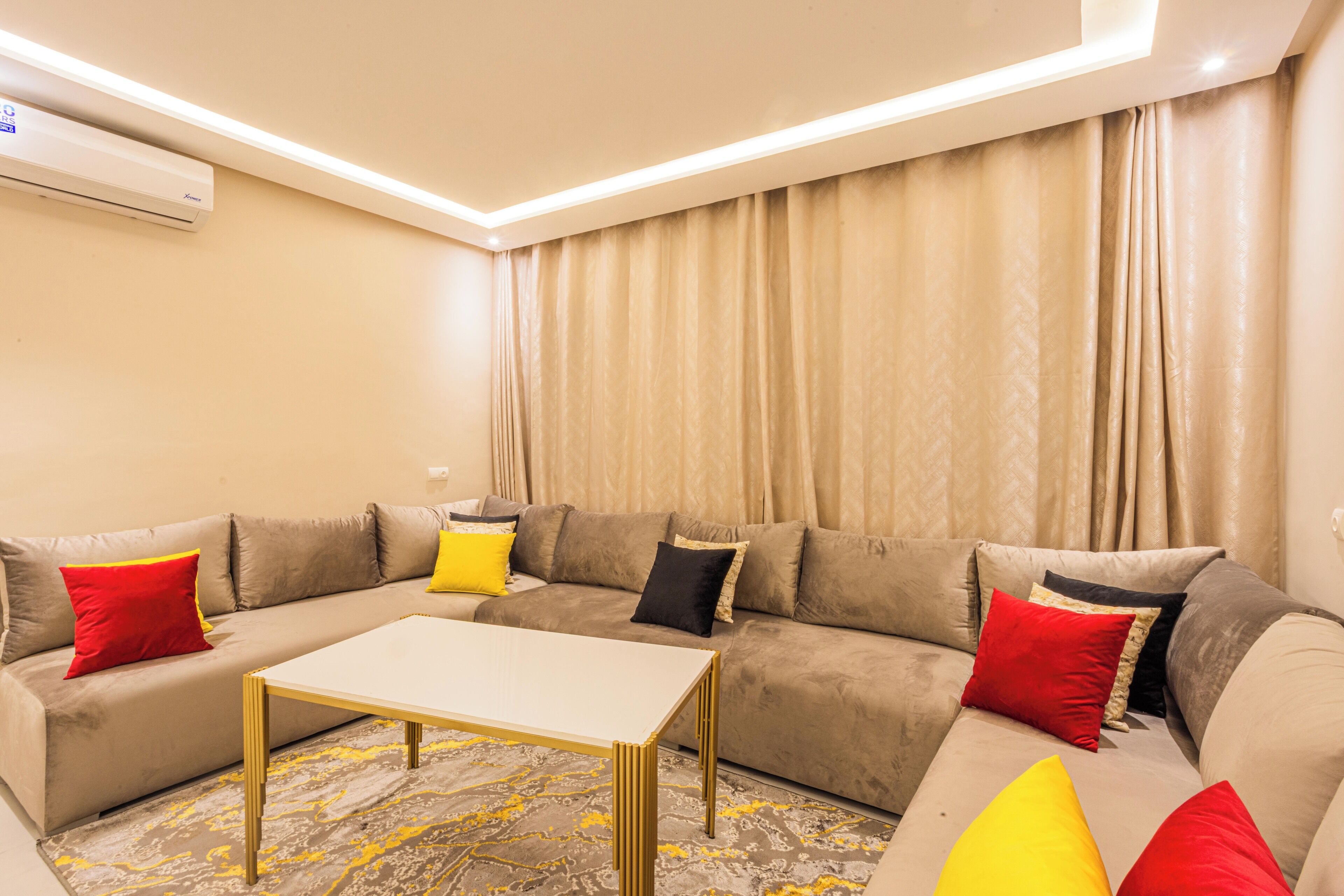 A modern living room with a sectional sofa, a coffee table, and a large window with curtains.