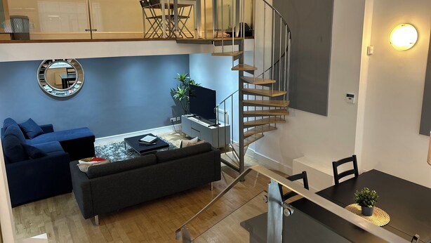 Eine moderne Wohnung mit Loftsitzung, Essbereich und einer Treppe zu einer oberen Etage.