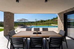 Une terrasse extérieure avec une table et des chaises, une piscine et une vue sur le paysage environnant.