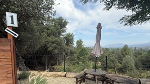 Une terrasse en bois avec une table de pique-nique et un parasol, entourée de gravier et de verdure.