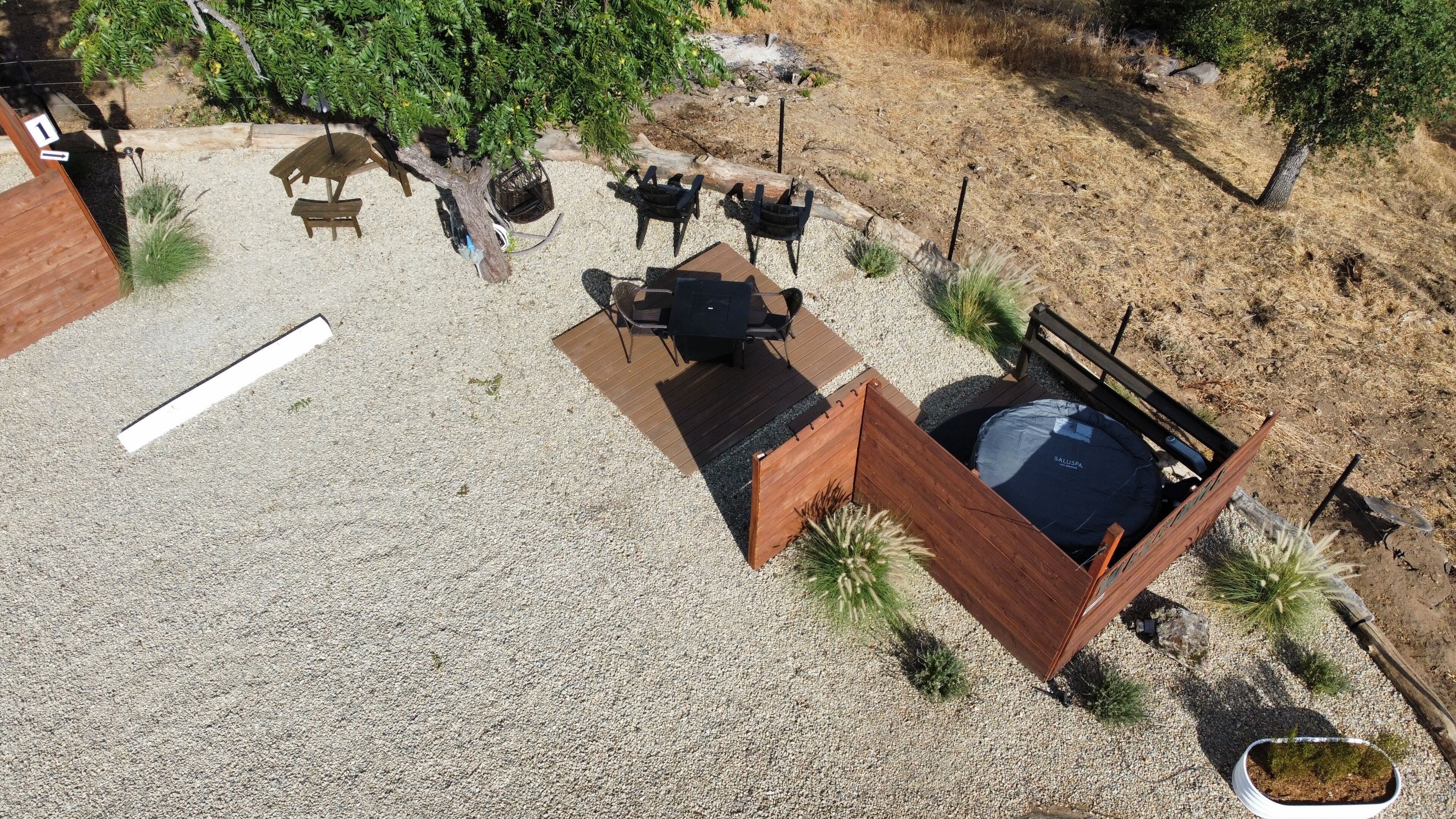 Un espace extérieur aménagé avec une table et des chaises, entouré de gravier et de plantes.