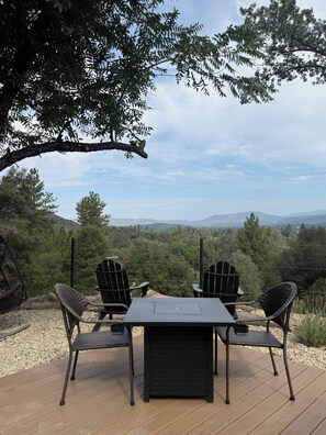 An outdoor seating area with a table and chairs, overlooking a mountainous landscape.