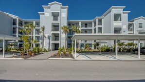 A modern multi-story hotel with a covered parking area and palm trees. - Modern Heritage Landing Condo – Resort Lifestyle (Punta Gorda)