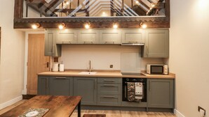 Una cocina moderna con armarios grises, una mesa de madera y un microondas empotrado.
