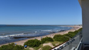 Une plage avec une digue rocheuse, un ciel bleu dégagé et une vue sur la mer.