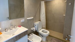 Une salle de bain équipée d’un lavabo, de toilettes, d’un bidet et d’une douche.
