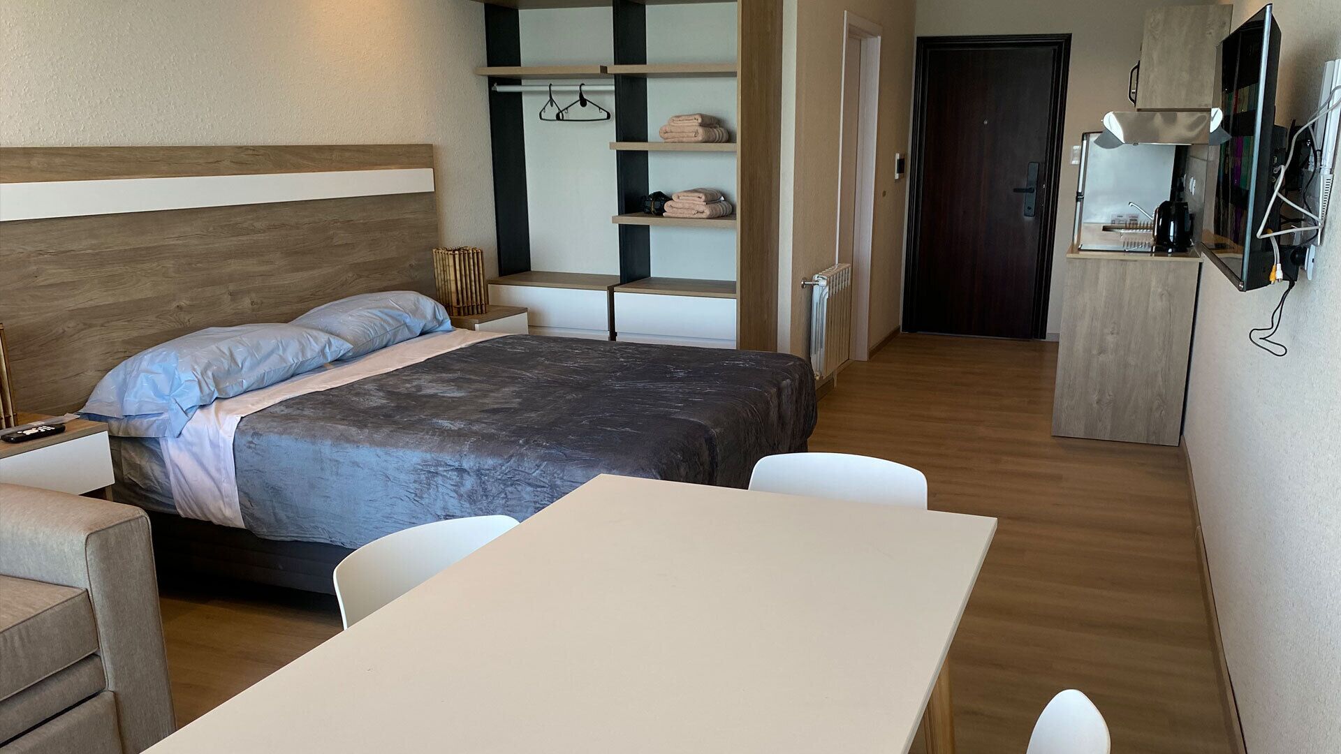 Un dormitorio moderno con cama, mesita de noche y una pequeña zona de escritorio con silla.