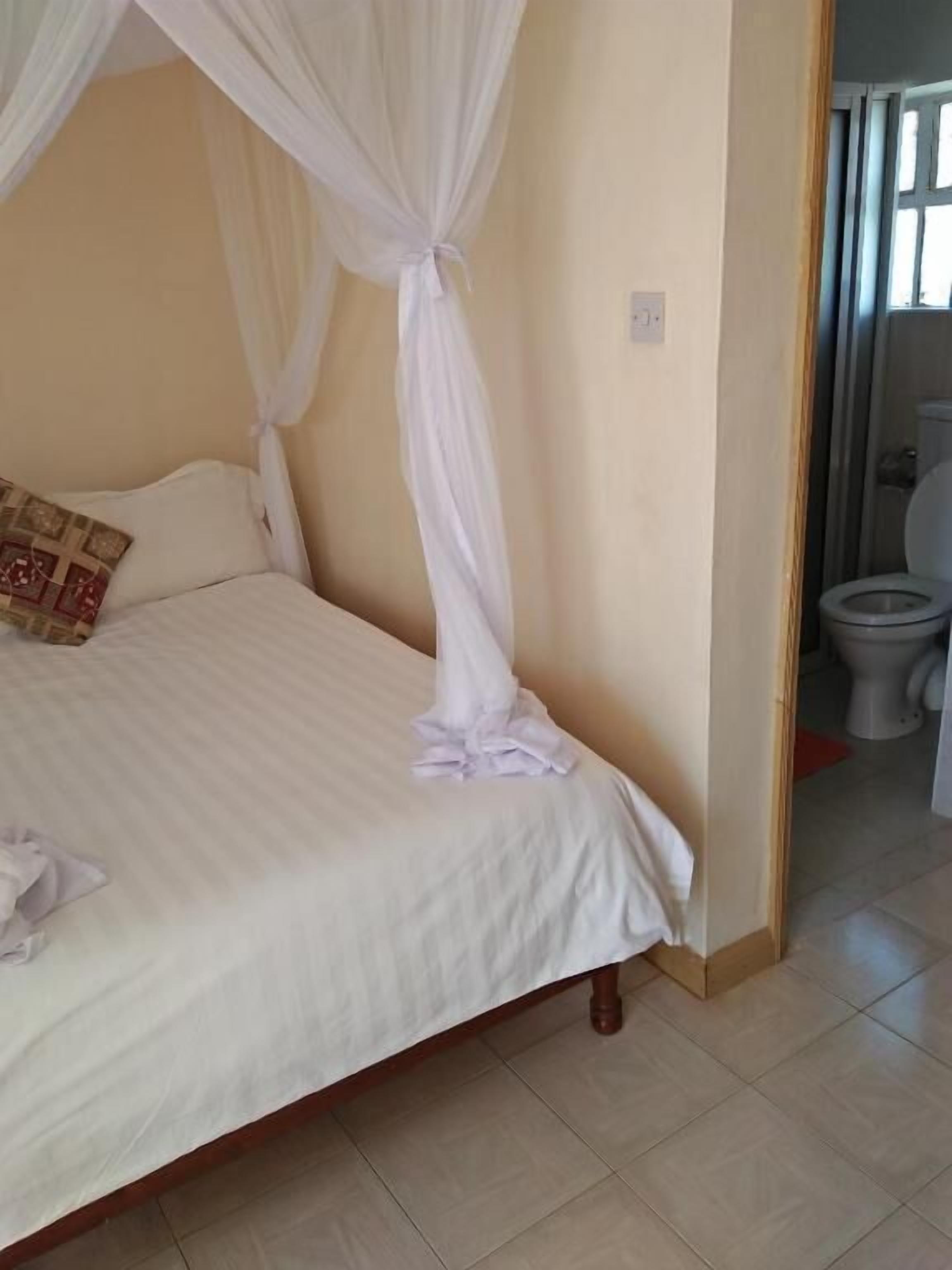 A neatly made bed with a canopy, a pillow, and a small bedside table.