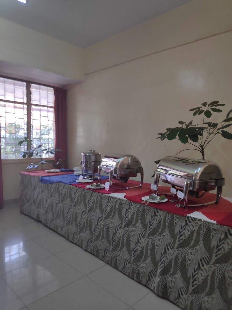 A buffet setup with a table covered in a patterned tablecloth, a grill, and a buffet station.
