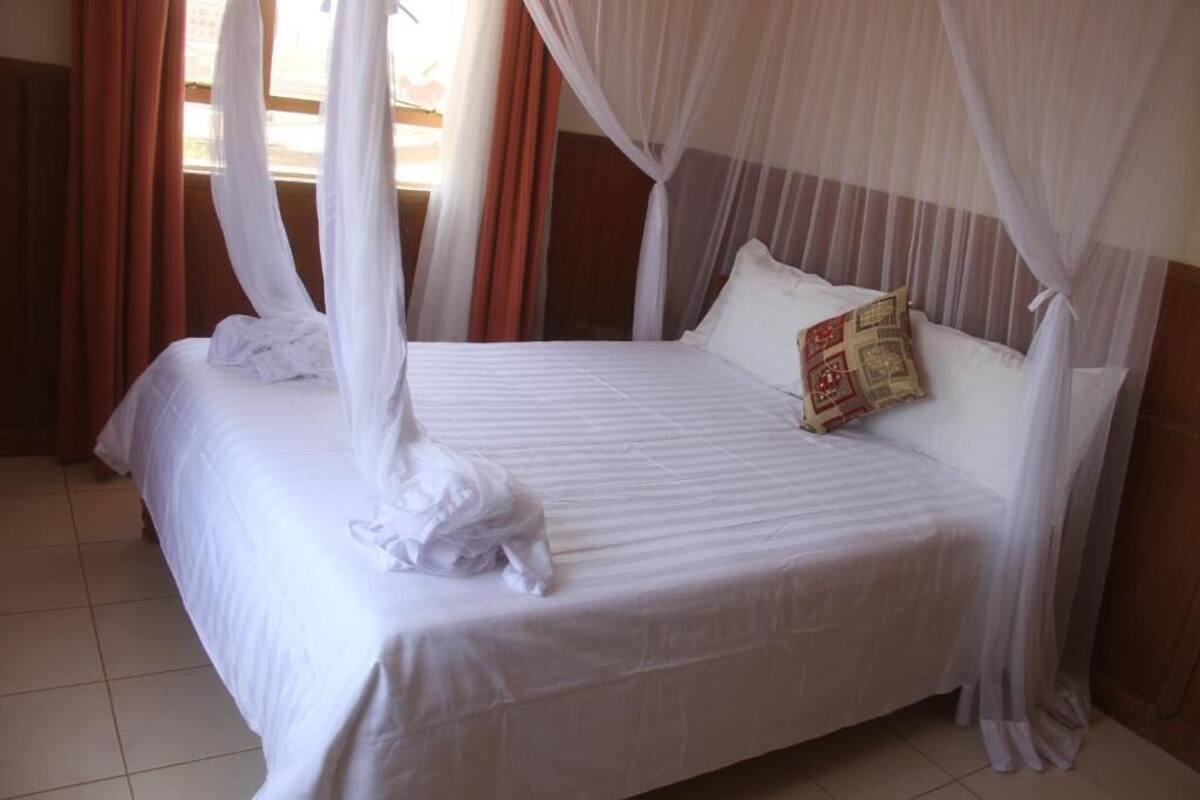 Un lit à baldaquin, avec une literie blanche et un coussin décoratif.