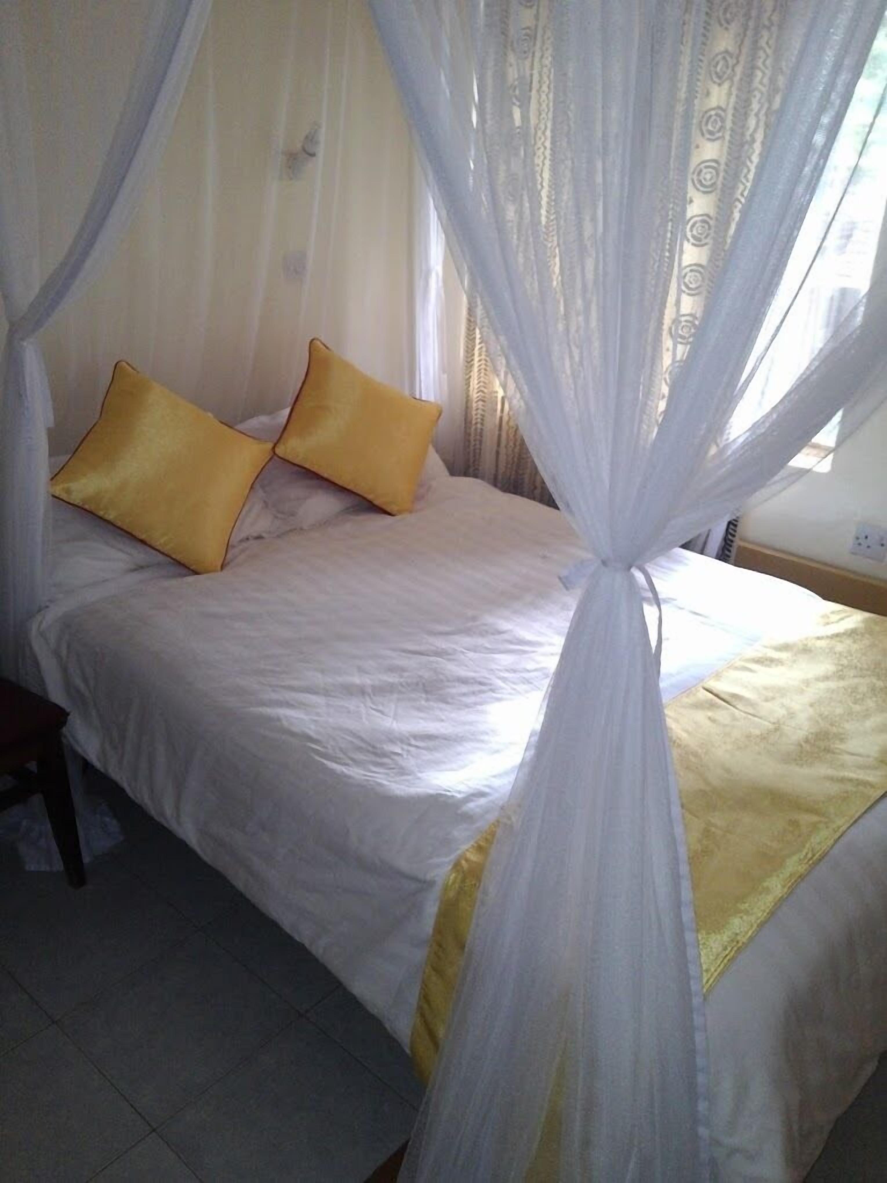A bed with a canopy, two pillows, and a bedside table.