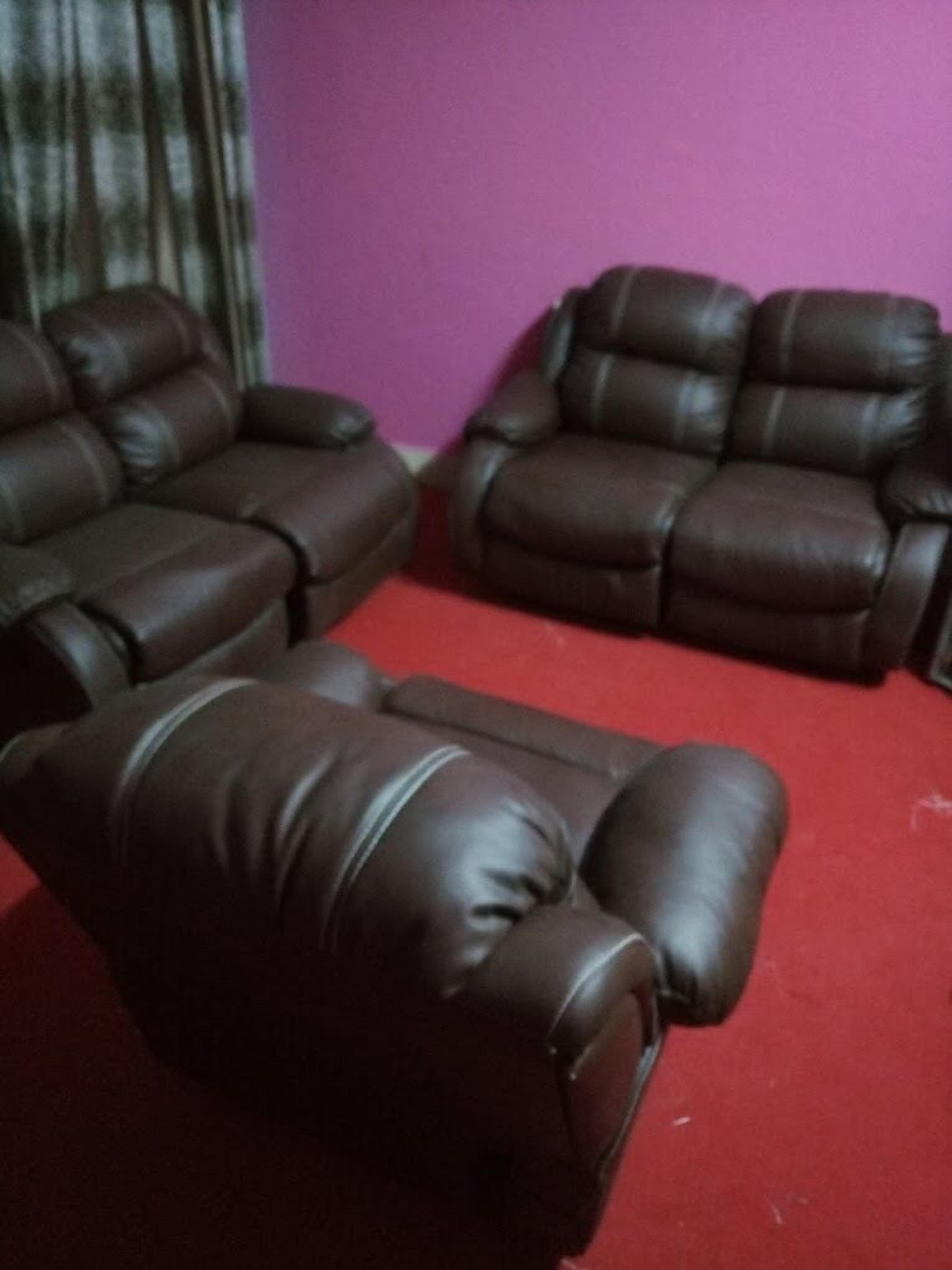 A room with two leather sofas and a red carpet.