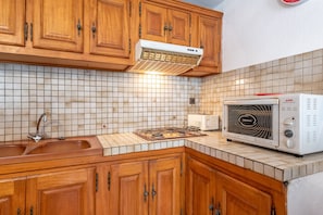 A kitchen with wooden cabinets, a tiled backsplash, a sink, a stove, and a built-in oven. - Panoramic South-Facing Apartment with Mountain Views (Grust)