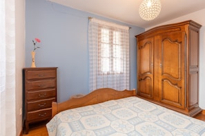 A bedroom with a wooden bed, a dresser, a wardrobe, and a window with sheer curtains. - Panoramic South-Facing Apartment with Mountain Views (Grust)