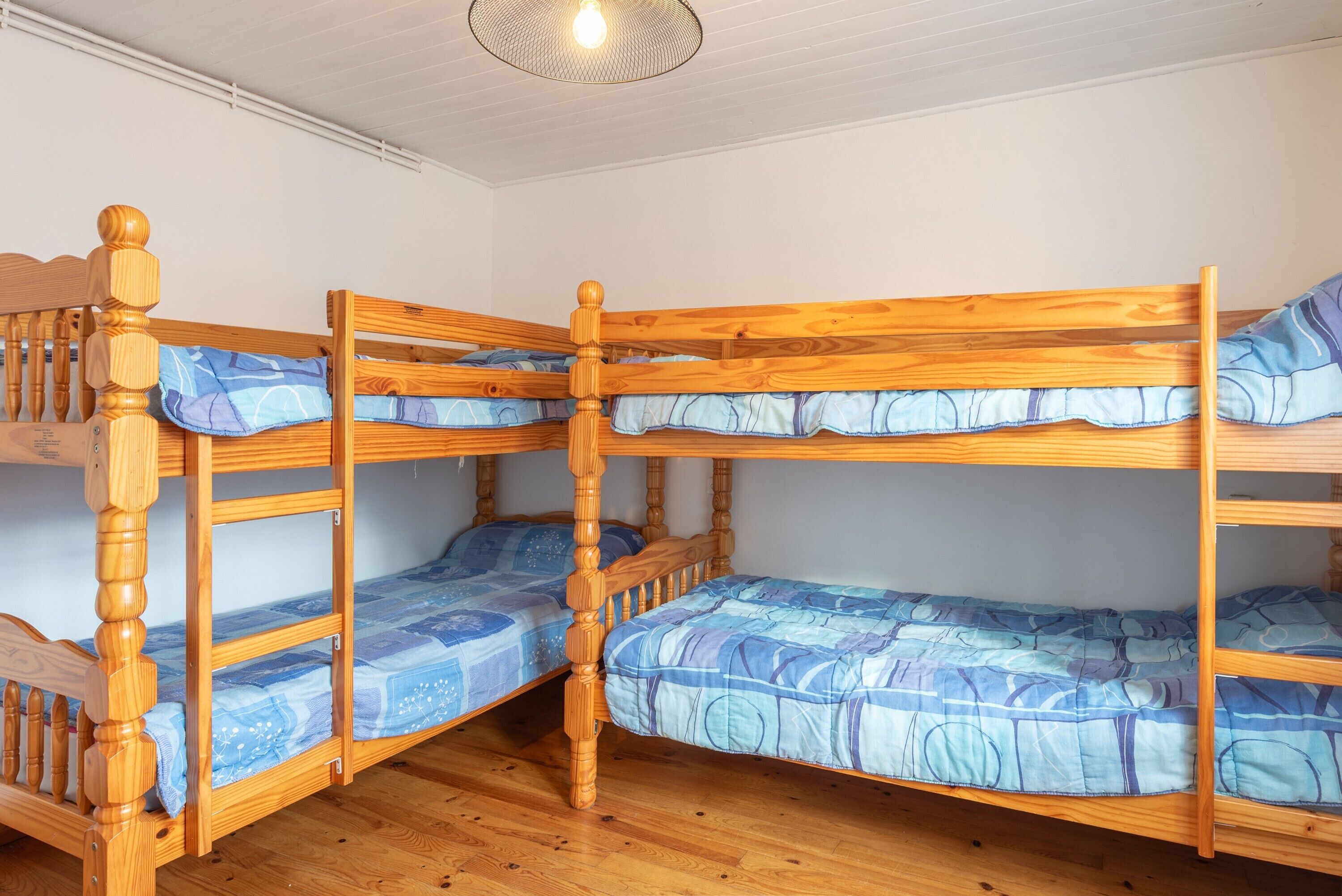 Une chambre avec un lit superposé en bois, un luminaire au plafond et une fenêtre.