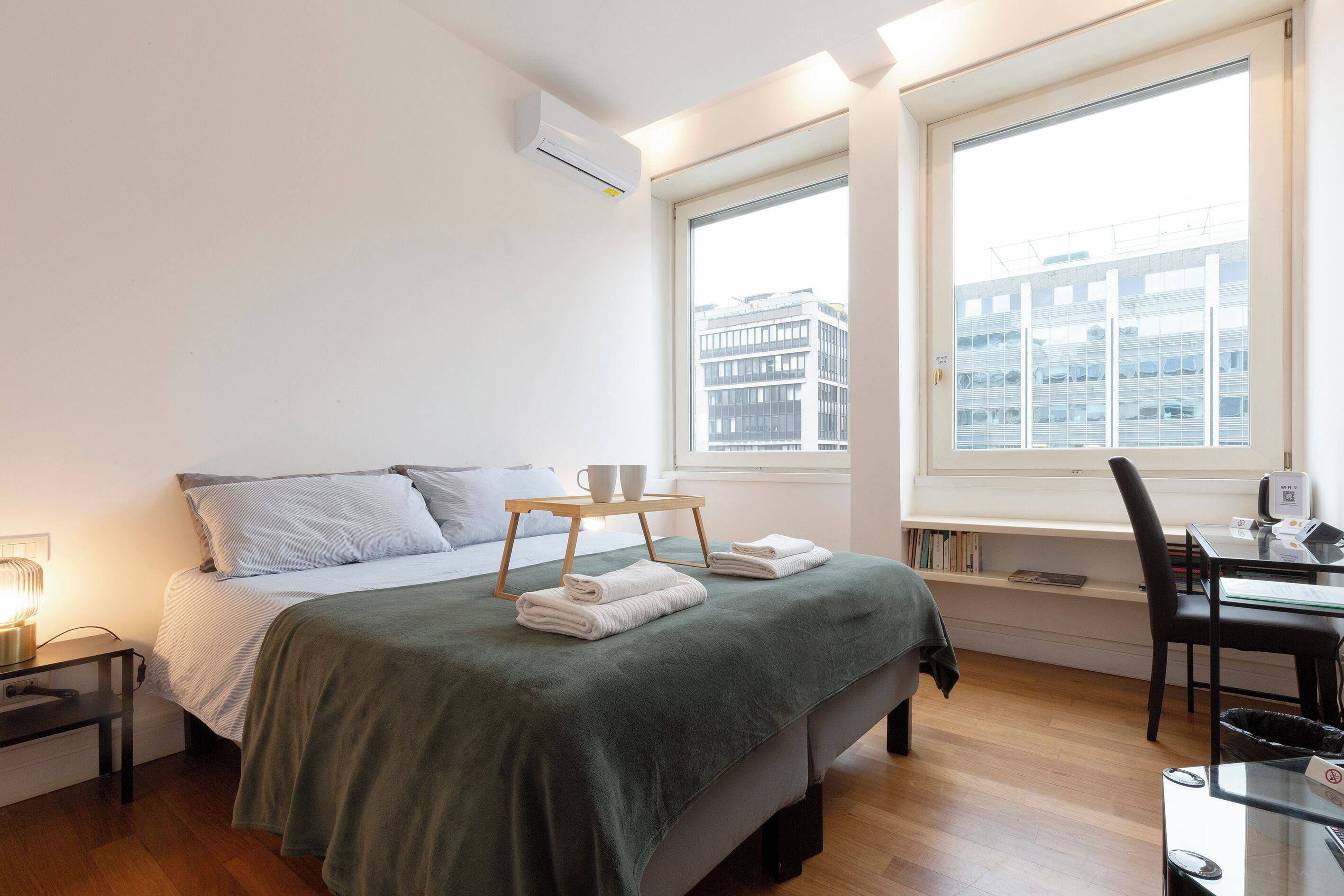 A modern bedroom with a bed, bedside table, and a desk with a chair.