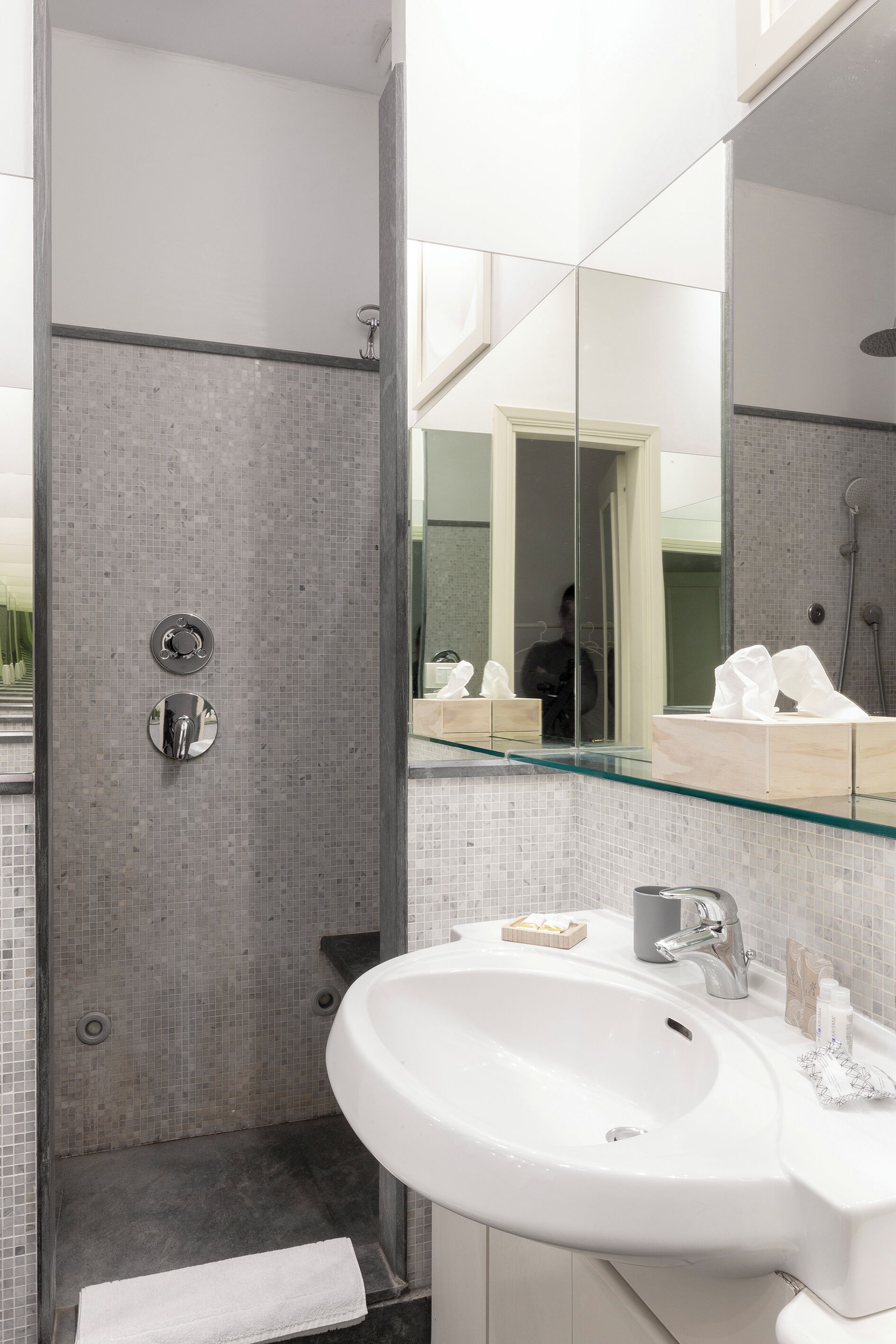 Une salle de bain moderne avec une douche à parois de verre, un lavabo blanc et un grand miroir.